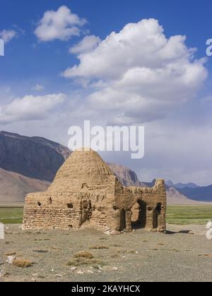 Vista panoramica verticale del vecchio caravanserai o della tomba cinese circondata da montagne a Bash Gumbaz vicino ad Alichur, Gorno-Badakshan, Tagikistan Pamir Foto Stock