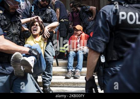 La polizia italiana rimuove un attivista della rete 'noi rimaniamo umani' che è stato incatenato davanti al Ministro italiano delle infrastrutture e dei Trasporti per protestare contro le politiche di immigrazione del governo italiano a Roma, in Italia, il 11 luglio 2018. (Foto di Michele Spatari/NurPhoto) Foto Stock