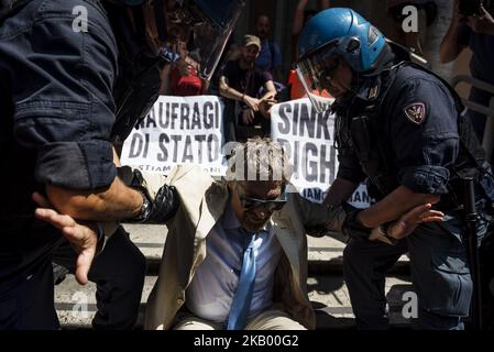 La polizia italiana rimuove un attivista della rete 'noi rimaniamo umani' che è stato incatenato davanti al Ministro italiano delle infrastrutture e dei Trasporti per protestare contro le politiche di immigrazione del governo italiano a Roma, in Italia, il 11 luglio 2018. (Foto di Michele Spatari/NurPhoto) Foto Stock