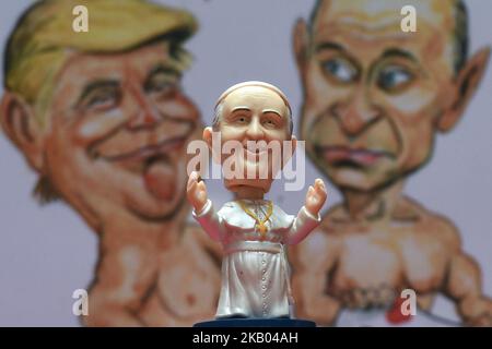 Un piccolo Papa Francis Bobble si trova davanti a una caricatura acquerello in cui sono presenti il presidente Donald Trump e il presidente Vladimir Putin, realizzati da un artista irlandese Ray Sherlock, in mostra alla balla Ban Art Gallery di Dublino. Il proprietario della galleria Frank o'Dea li darà gratuitamente con ogni acquisto effettuato durante la visita del Papa in Irlanda. Papa Francesco visiterà l'Irlanda dal 21 al 26 agosto in quella che sarà la prima visita papale da quando il Papa Giovanni Paolo II arrivò nel 1979. Mercoledì 18 2018 luglio a Dublino, Irlanda. (Foto di Artur Widak/NurPhoto) Foto Stock