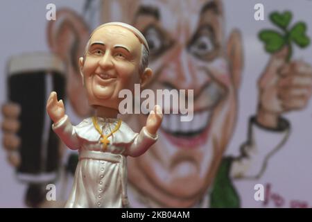 Una piccola testa di Papa Francis Bobble davanti ad una caricatura acquerello che presenta Papa Francis che alloggia una pinta di Guinness e shamrock, realizzata da un artista irlandese Ray Sherlock, in mostra alla Sala Ban Art Gallery di Dublino. Il proprietario della galleria Frank o'Dea li darà gratuitamente con ogni acquisto effettuato durante la visita del Papa in Irlanda. Papa Francesco visiterà l'Irlanda dal 21 al 26 agosto in quella che sarà la prima visita papale da quando il Papa Giovanni Paolo II arrivò nel 1979. Mercoledì 18 2018 luglio a Dublino, Irlanda. (Foto di Artur Widak/NurPhoto) Foto Stock