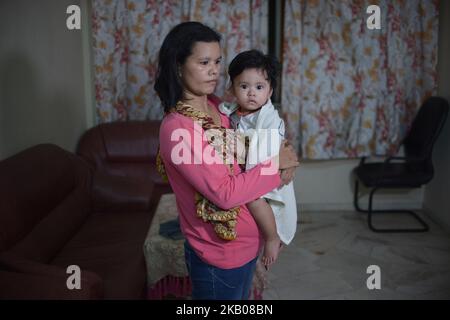 Una donna migrante tiene il suo bambino mentre l'ufficiale dell'immigrazione della Malesia controlla la sua casa durante un raid a Subang Jaya, fuori Kuala Lumpur, Malesia, 29 luglio 2018. Circa 157 migranti non documentati sono stati arrestati per vari reati dal Dipartimento dell'immigrazione durante un raid nell'ambito dell'operazione "Ops Mega 3,0" contro lavoratori migranti non documentati. (Foto di Zahim Mohd/NurPhoto) Foto Stock