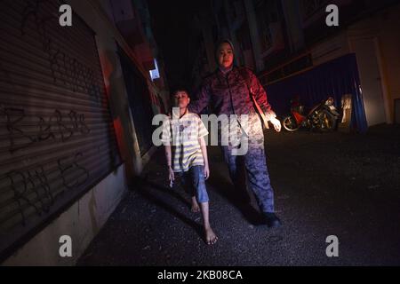 Un ufficiale dell'immigrazione (R) accompagna un ragazzo (L) che sua madre ha arrestato durante un raid a Subang Jaya, al di fuori di Kuala Lumpur, Malesia, 29 luglio 2018. Circa 157 migranti non documentati sono stati arrestati per vari reati dal Dipartimento dell'immigrazione durante un raid nell'ambito dell'operazione "Ops Mega 3,0" contro lavoratori migranti non documentati. (Foto di Zahim Mohd/NurPhoto) Foto Stock