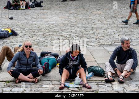 Pellegrini che riposano a Praza do Obradoiro, dove si trova la Cattedrale di Santiago, in Spagna, il 25 luglio 2018. Il Camino de Santiago (la Via di San Giacomo) è una grande rete di antiche vie di pellegrinaggio che si estendono in tutta Europa e si riuniscono presso la tomba di San Giacomo (Santiago in spagnolo) a Santiago de Compostela, nel nord-ovest della Spagna. Ogni anno, centinaia di migliaia di persone di varie origini camminano il Camino de Santiago da soli o in gruppi organizzati. Il percorso più popolare (che diventa molto affollato a metà estate) è il Camino Francés che si estende per 780 km (n Foto Stock