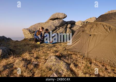 Famiglia di viaggiatori che consumata la colazione fuori dalla tenda Foto Stock