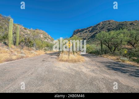 Sentiero escursionistico con strade asfaltate e segnaletica contro montagna e cielo blu Foto Stock