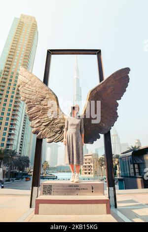 Dubai, Emirati Arabi Uniti - 12th ottobre 2022: Posa turistica caucasica femminile delle ali del Messico scultura moderna di Jorge Marin e Burj Khalifa edificio nel Foto Stock