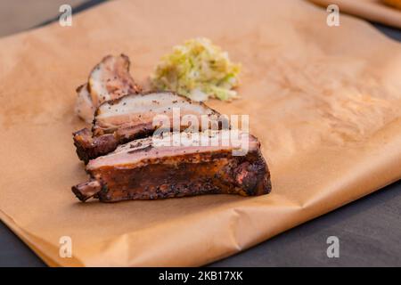 Fette di costolette di manzo su carta artigianale sul tavolo al festival estivo del cibo locale. Foto Stock