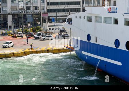 Pireo, Atene, Grecia - 2022 giugno: Grande traghetto guidato in attracco da un operaio nel porto del Pireo. Foto Stock