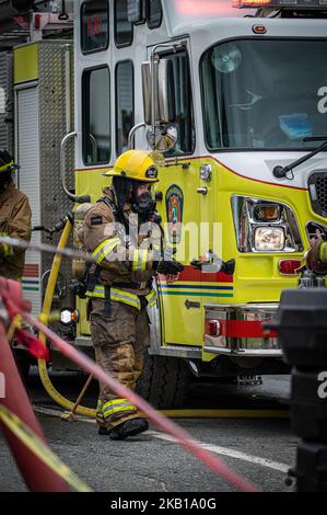 Rouyn-Noranda, Quebec, Canada, 06-15-2022 - pompiere esausto dopo aver combattuto un fuoco di casa e aver gettato i guanti Foto Stock