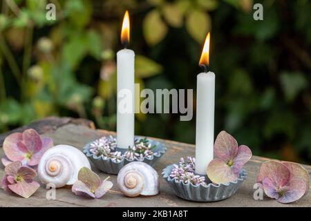 sistemazione romantica con candele bianche, corona di erica e fiori di ortensia Foto Stock