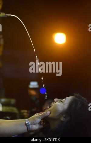 Giovani donne e donne nepalesi bevono la birra di riso sbocca dalla bocca l'enorme maschera di idolo Swet Bharab durante il Festival Indra Jatra celebrato a Basantapur Durbar Square, Kathmandu, Nepal Mercoledì, 26 settembre 2018. Indra Jatra è la celebrazione del giorno di Dio Indra, il re dei cieli. Indra Jatra è festival si celebra in Basantapur Durbar Square, Kathmandu, Nepal. Indra Jatra è uno dei festival importanti del Nepal che celebra la fine del monsone. Il festival più grande in cui Kumari si presenta al pubblico è Indra Jatra. Il giorno seguente il carro di Kumari, Bhaira Foto Stock