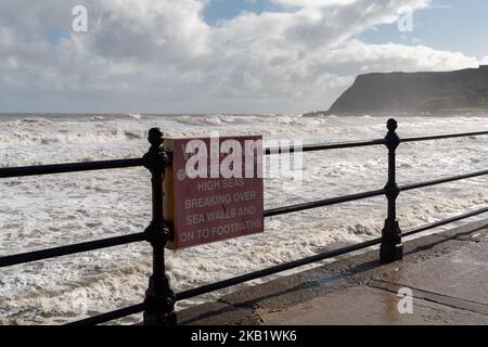 Scarborough, Regno Unito: Segnale di avvertimento di pericolo dall'alto mare che si infrana sulle pareti e sui sentieri in alta marea sulla costa di North Bay. Foto Stock