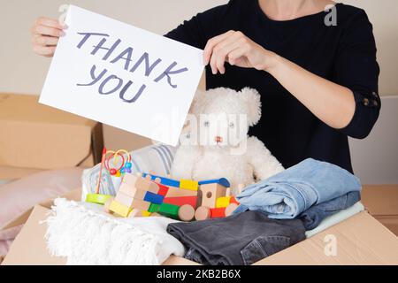 Grazie per la donazione. Volontari che raccolgono donazioni per beneficenza. Donna mani tenendo foglio di carta con messaggio grazie su scatole di cartone pieno Foto Stock