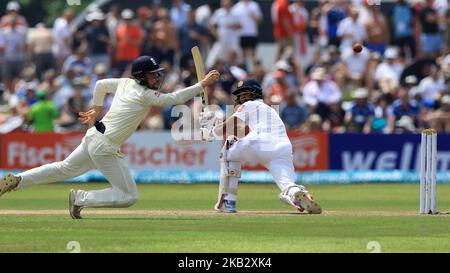 Inghilterra il cricket Rory Burns (L) si tuffa per catturare la palla mentre il capitano di cricket dello Sri Lanka Dinesh Chandimal guarda durante il gioco di 2nd giorni della prima partita di cricket di prova tra Sri Lanka e Inghilterra allo stadio di cricket internazionale di Galle, Galle, Sri Lanka, il 7 novembre 2018. (Foto di Tharaka Basnayaka/NurPhoto) Foto Stock