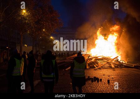 Parigi, Francia, 24 novembre 2018. I manifestanti hanno creato una barricata durante una protesta dei giubbotti gialli (Gilets jaunes) contro l'aumento dei prezzi del petrolio e dei costi della vita nei pressi dell'Arco di Trionfo sul viale foch. Le forze di sicurezza di Parigi hanno sparato gas lacrimogeno e cannone ad acqua per disperdere i manifestanti. (Foto di Emeric Fohlen/NurPhoto) Foto Stock