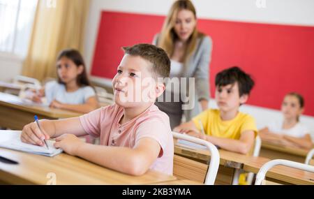 Sorridente diligente presteen ragazzo che studia con compagni di classe Foto Stock