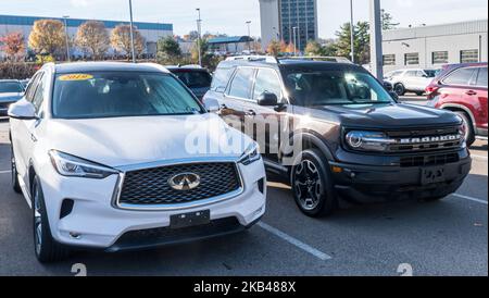 Due veicoli, un Infiniti bianco e un SUV Ford Bronco in vendita presso una concessionaria a Monroeville, Pennsylvania, USA Foto Stock