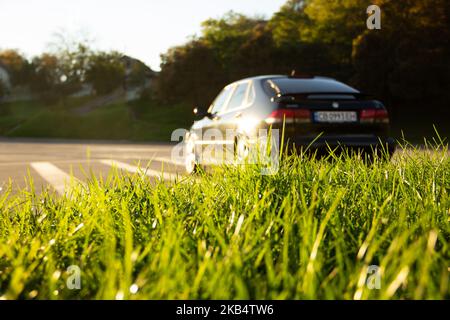 Ucraina, Chernihiv - 10 ottobre 2022: Vecchia auto svedese Saab 9-3 Aero sulla strada. Erba in primo piano Foto Stock