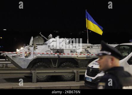 Un poliziotto ucraino si trova vicino a un'auto blindata, durante un'operazione di forze speciali ucraine per detenere un uomo che minacciava di far esplodere un ponte importante sul fiume Dnipro a Kiev, in Ucraina, il 18 settembre 2019. I membri della speciale Ucraina nella capitale Ucraina hanno sequestrato un uomo armato che minacciava di far esplodere il fiume Dnipro a Kiev. Secondo quanto riferito, un uomo sconosciuto sparò e minacciò di esplodere un ponte sul fiume Dnipro. La polizia prevede di avviare un procedimento penale contro l'accusa di "tracciare un atto terroristico”. Prima dell'arresto, l'uomo gettò awa Foto Stock