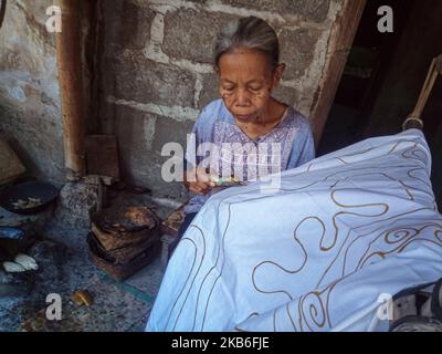 Un'artista batik donna che crea vari disegni con uno strumento simile a una penna chiamato un cantare come parte del processo di fabbricazione indonesiano batik a Bantul, Yogyakarta, Indonesia il 21 settembre 2019. Batik è un panno che viene tradizionalmente realizzato utilizzando una tecnica generica di tintura resistente alle cere. (Foto di Rizqullah Hamiid/NurPhoto) Foto Stock