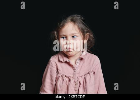 ragazza carina che fa i volti espressivi in studio su uno sfondo nero Foto Stock