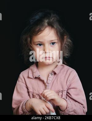 ragazza carina che fa i volti espressivi in studio su uno sfondo nero Foto Stock