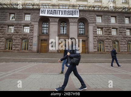 La gente passa davanti a una bandiera che legge 'No alla capitolazione!', contro l'attuazione della cosiddetta 'Steinmeier Formula', che ha installato sopra l'ingresso al municipio di Kyiv, Ucraina, il 04 ottobre 2019. Il 1 ottobre, 2019 membri del Gruppo di contatto trilaterale sull'Ucraina hanno accettato un processo di pace noto come "Steinmeier Formula", come hanno riferito i media locali. (Foto di Str/NurPhoto) Foto Stock