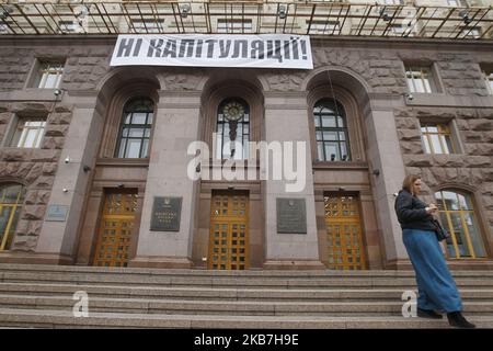 Una donna passa davanti a una bandiera che legge 'No alla capitolazione!', contro l'attuazione della cosiddetta 'Steinmeier Formula', che ha installato sopra l'ingresso al municipio di Kyiv, Ucraina, il 04 ottobre 2019. Il 1 ottobre, 2019 membri del Gruppo di contatto trilaterale sull'Ucraina hanno accettato un processo di pace noto come "Steinmeier Formula", come hanno riferito i media locali. (Foto di Str/NurPhoto) Foto Stock