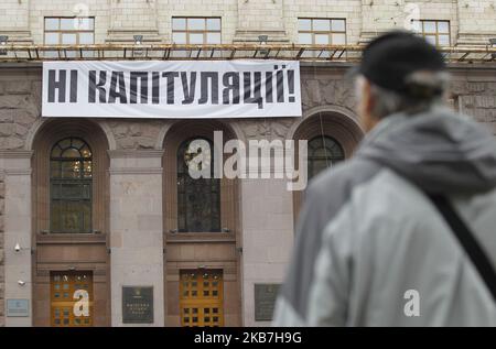 Un uomo guarda su un banner che legge 'No alla capitolazione!', contro l'attuazione della cosiddetta 'Steinmeier Formula', che ha installato sopra l'ingresso al municipio di Kyiv, in Ucraina, il 04 ottobre 2019. Il 1 ottobre, 2019 membri del Gruppo di contatto trilaterale sull'Ucraina hanno accettato un processo di pace noto come "Steinmeier Formula", come hanno riferito i media locali. (Foto di Str/NurPhoto) Foto Stock