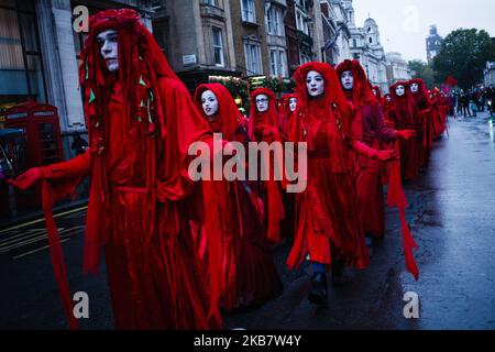 La 'Red Rebel Brigade' marcia silenziosamente lungo Whitehall come membri del gruppo attivista per il cambiamento climatico Extinction Rebellion (XR) blocca le strade il giorno di apertura della sua lunga ribellione internazionale a Londra, Inghilterra, il 7 ottobre 2019. I membri del gruppo intendono occupare 12 siti intorno agli edifici governativi di Westminster almeno fino a sabato 19 ottobre prossimo, con l'obiettivo di "mettere in secondo piano" l'area per esercitare pressioni sui legislatori affinché intraprendano ulteriori e più rapidamente azioni per arrestare la perdita di biodiversità e ridurre le emissioni di gas a effetto serra. Blocchi simili di estinzione Rebell Foto Stock