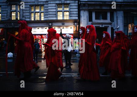 La 'Red Rebel Brigade' marcia silenziosamente lungo Whitehall come membri del gruppo attivista per il cambiamento climatico Extinction Rebellion (XR) blocca le strade il giorno di apertura della sua lunga ribellione internazionale a Londra, Inghilterra, il 7 ottobre 2019. I membri del gruppo intendono occupare 12 siti intorno agli edifici governativi di Westminster almeno fino a sabato 19 ottobre prossimo, con l'obiettivo di "mettere in secondo piano" l'area per esercitare pressioni sui legislatori affinché intraprendano ulteriori e più rapidamente azioni per arrestare la perdita di biodiversità e ridurre le emissioni di gas a effetto serra. Blocchi simili di estinzione Rebell Foto Stock