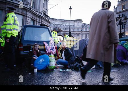 A man walks past members of climate change activist group Extinction Rebellion (XR) demonstrate beside a hearse, carrying a coffin for 'Our Future', in Trafalgar Square on the second day of the group's 'International Rebellion' in London, England, on October 8, 2019. By early Tuesday evening the Metropolitan Police were reporting that a total of 531 arrests had been made over the two days of protests in the city so far, with police officers working to clear people and tents from many of the sites taken over by activists yesterday. Similar blockades by Extinction Rebellion in April, at sites in Stock Photo