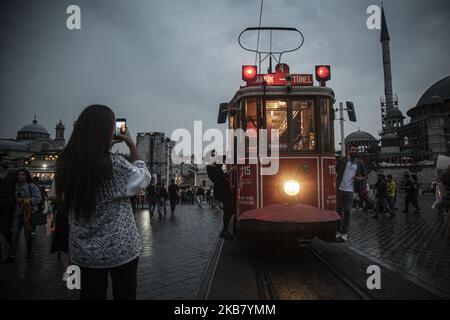 I turisti scattano foto ricordo con un tram rosso vecchio stile in Piazza Taksim e Via Istiklal in una giornata piovosa e fredda. La zona di Taksim di Istanbul è famosa per i suoi negozi, ristoranti, caffè, bar e discoteche 08 ottobre 2019, Istanbul, Turchia Istanbul (Foto di Momen Faiz/NurPhoto) Foto Stock