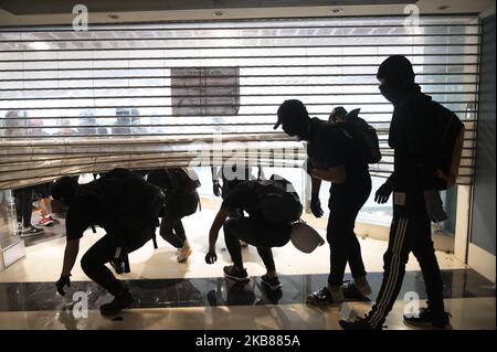 Un manifestante è visto uscire da una porta distrutta durante una protesta anti-governativa nel centro commerciale New Town Plaza di Hong Kong, Cina, 13 ottobre 2019. I manifestanti della Pro-democrazia sono scese in strada da alcuni mesi a Hong Kong per protestare. (Foto di Vernon Yuen/NurPhoto) Foto Stock