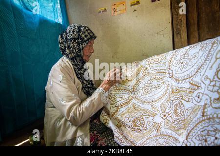 Un'artista batik donna che crea vari disegni con uno strumento simile a una penna chiamato un cantare come parte del processo di fabbricazione indonesiano batik a Bantul, Yogyakarta, Indonesia il 15 ottobre 2019. Batik è l'arte e la cultura originale dell'Indonesia fatta con un panno che tradizionalmente sta usando una tecnica generica di tintura cera-resistente. (Foto di Rizqullah Hamiid/NurPhoto) Foto Stock