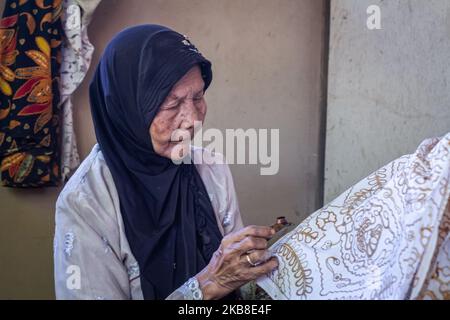 Un'artista batik donna che crea vari disegni con uno strumento simile a una penna chiamato un cantare come parte del processo di fabbricazione indonesiano batik a Bantul, Yogyakarta, Indonesia il 15 ottobre 2019. Batik è l'arte e la cultura originale dell'Indonesia fatta con un panno che tradizionalmente sta usando una tecnica generica di tintura cera-resistente. (Foto di Rizqullah Hamiid/NurPhoto) Foto Stock