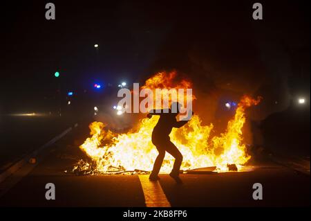 Un protester lancia pietre e bottiglie di vetro da dietro la barricata di fuoco. Migliaia di catalani sono tornati per le strade di Barcellona per il secondo giorno consecutivo protestando contro la sentenza della Corte Suprema in cui sono stati imprigionati nove leader politici indipendenti. (Foto di Charlie PÃ©rez/NurPhoto) Foto Stock