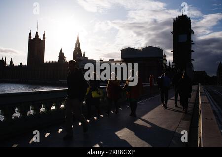 La gente attraversa il Westminster Bridge di fronte al Parlamento mentre il sole inizia a tramontare a Londra, in Inghilterra, il 17 ottobre 2019. Il primo ministro Boris Johnson ha concordato oggi un nuovo accordo di ritiro con l'Unione europea, ma non è chiaro se l'accordo passerà un voto sui beni comuni fissato per questo sabato, in una sessione speciale del fine settimana dei parlamentari. Il Partito democratico Unionista (DUP), visto come un influente sostenitore di una sciata di deputati del Partito conservatore pro-Brexit, ha detto senza senso di non sostenere l’accordo. (Foto di David Cliff/NurPhoto) Foto Stock