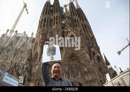 Un turista che visita il Tempio di â€œSagrada Familiaâ€ incoraggia un ritratto di Re Felipe VI sul suo volto, mentre gli appassionati di picnic cantavano per l'indipendenza, a Barcellona, in Spagna, il 18 ottobre 2019. Picnic per la Repubblica ha creato un'iniziativa cittadina per la celebrazione di un picnic di protesta di fronte alla Sagrada Familia per esteriorizzare il conflitto catalano ai turisti. (Foto di Charlie PÃ©rez/NurPhoto) Foto Stock