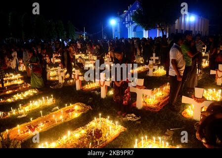 I cattolici del Bangladesh pregano dopo aver acceso le candele per i loro parenti defunti in un cimitero di Dhaka, Bangladesh, il 02 novembre 2019. I devoti cristiani osservano il giorno di tutte le anime, conosciuto come la Festa di tutte le anime, la Commemorazione di tutti i fedeli defunti. In questo giorno, i cristiani vengono nel cimitero e pregano per le anime defunte dei loro cari. All Soul's Day è un giorno cattolico romano di memoria per gli amici e i cari che sono passati. Ciò deriva dall'antica festa pagana dei morti, che celebrava la credenza pagana che le anime dei morti sarebbero ritornate per un pasto Foto Stock