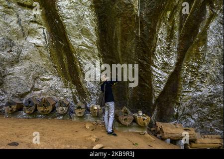 Poso, Sulawesi centrale, Indonesia (novembre 2): Un visitatore fotografa una fila di bare nell'area della Riserva Culturale della Grotta di Pamona a Tentena, Poso Regency, Provincia di Sulawesi centrale, Indonesia il 2 novembre 2019. La grotta lunga 200 metri con una profondità di 80 metri è un deposito per i resti della tribù di Pamona o delle popolazioni indigene della Reggenza di Poso. Si pensa che gli antenati di Pamona esistessero nell'età della pietra intorno al 2000 a.C. (Foto di Basri Marzuki/NurPhoto) Foto Stock