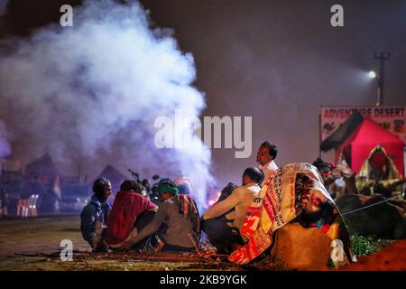 I venditori di cammelli si scaldano durante la notte fredda dopo la pioggia pesante alla fiera di Pushkar, Rajasthan, India, 03 novembre 2019.Thouses dei commercianti di bestiame dalla regione vengono alla fiera tradizionale del cammello dove il bestiame, principalmente cammelli, è commerciato. La fiera annuale del cammello e del bestiame è una delle più grandi fiere mondiali del cammello. (Foto di Vishal Bhatnagar/NurPhoto) Foto Stock