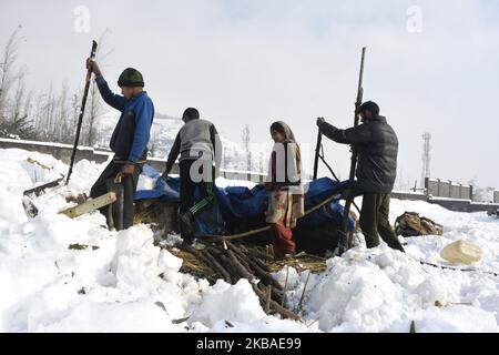 Le persone nomadi hanno ripulito la tenda di fortuna dopo che è stata dannata da forti nevicate nella periferia di Srinagar, indiano amministrato kashmir il 08 novembre 2019. La valle del Kashmir ha ricevuto la sua prima nevicata il giovedì che ha danneggiato la proprietà in molti luoghi ha provocato l'uccisione di sette persone. (Foto di Muzamil Mattoo/NurPhoto) Foto Stock