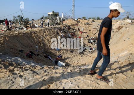 Un palestinese vicino ad un cratere fatto durante la notte scioperi missilistici israeliani che distrussero una casa e uccisero otto membri della famiglia Abu Malhous, a Deir al-Balah, nella striscia centrale di Gaza, giovedì 14 novembre, 2019. (Foto di Majdi Fathi/NurPhoto) Foto Stock