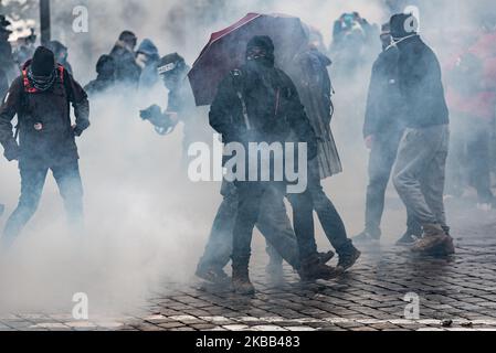 A demonstrator masked and hooded in black and sheltered under an umbrella stands in the middle of tear gas, this Saturday, November 16, 2019, while the anniversary demonstration of the Yellow Vests for the 1 year of the movement was held in Paris. A major demonstration was to be held between Place d'Italie and Gare du Nord, but following scenes of violence between the Black Bloc and the police, the prefecture cancelled the march, which gave way to scenes of chaos. (Photo by Samuel Boivin/NurPhoto) Stock Photo