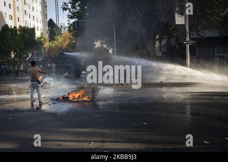 I dimostranti corrono come un veicolo di polizia utilizza il suo cannone ad acqua durante una protesta anti-governativa a Santiago, Cile, 31 ottobre 2019. (Foto di Jeremias Gonzalez/NurPhoto) Foto Stock