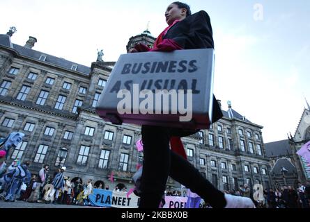 Gli attivisti della ribellione di estinzione si esibiscono durante la ribellione del Black Friday in Piazza Dam il 29 novembre 2019 ad Amsterdam, nei Paesi Bassi. I manifestanti chiedono l'attuale sistema dei consumi eccessivi, una sfilata di moda con venti modelli che indossano costumi con materiali riciclabili legati alla crisi climatica. L'industria della moda è destinata a consumare un quarto del budget mondiale di carbonio entro il 2050 nella produzione di abbigliamento. (Foto di Paulo Amorim/NurPhoto) Foto Stock