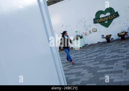 A woman walks past a wall of memorials to the victims of the June 2017 Grenfell Tower at the base of the remains of the tower in North Kensington in London, England, on December 2, 2019. Seventy-two people died in the blaze, the severity of which many local residents blamed afterwards on the impact of years of Conservative government neglect of the area and its social housing. For decades represented by Conservative Party MPs, North Kensington falls within the parliamentary constituency of Kensington, currently the most marginal in the whole of England, won off the Tories by the Labour Party a Stock Photo