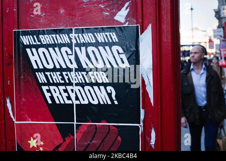 La gente cammina per un poster che chiede la solidarietà britannica con i manifestanti pro-democrazia a Hong Kong, presentati dal gruppo attivista "Fight for Freedom Stand with Hong Kong” su una cassetta telefonica a Whitehall a Londra, in Inghilterra, il 3 dicembre 2019. (Foto di David Cliff/NurPhoto) Foto Stock